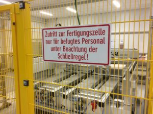 Sicherheitszelle um CNC Maschine mit Warnschild